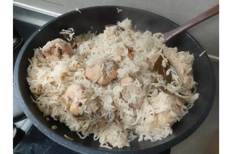 Freshly cooked chicken pulao with tender chicken pieces and long-grain basmati rice in a pan.